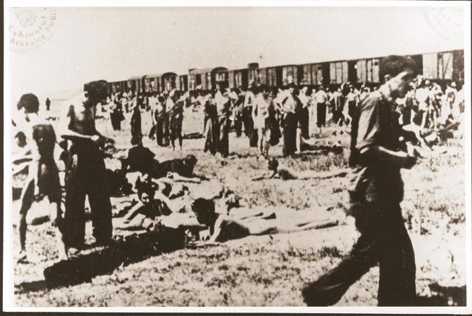 Jewish passengers on the Iasi death train rest in a field beside the tracks during a stop on the journey